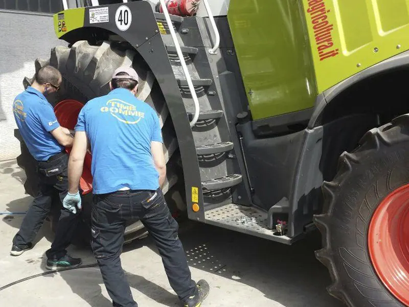Due tecnici al lavoro sulla ruota di una grande macchina agricola