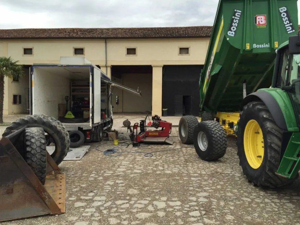 Un rimorchio agricolo in un cortile, accanto all’autocarro di soccorso