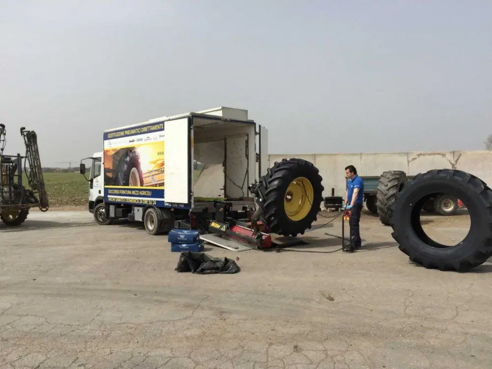 Un tecnico al lavoro su una gomma da trattore in un piazzale